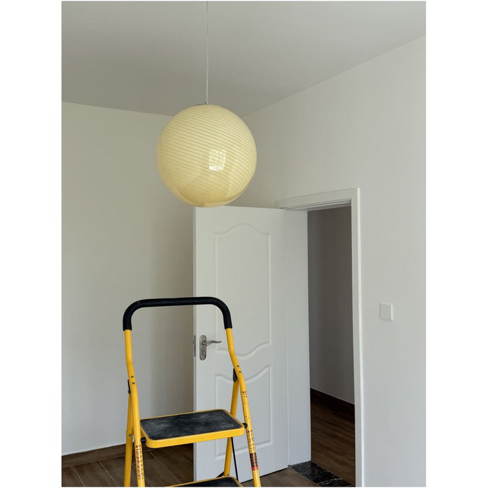 Cream pendant light installed in a hallway – the soft yellow swirl BO-HA Kaja glass globe on its cord.