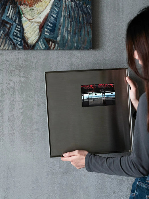 Minimalist metal wall art in brushed steel hung above a console in a modern interior
