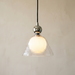 Hedda dimmable pendant light lit against a warm plaster wall, showing the clear ribbed bell over the opal inner globe