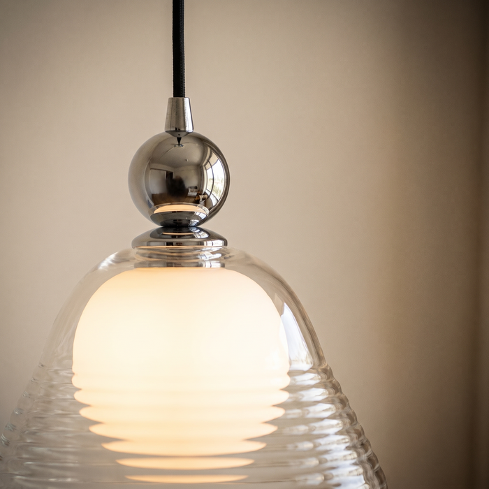Close detail of the polished chrome ball where the black cord enters the top of the Hedda glass shade